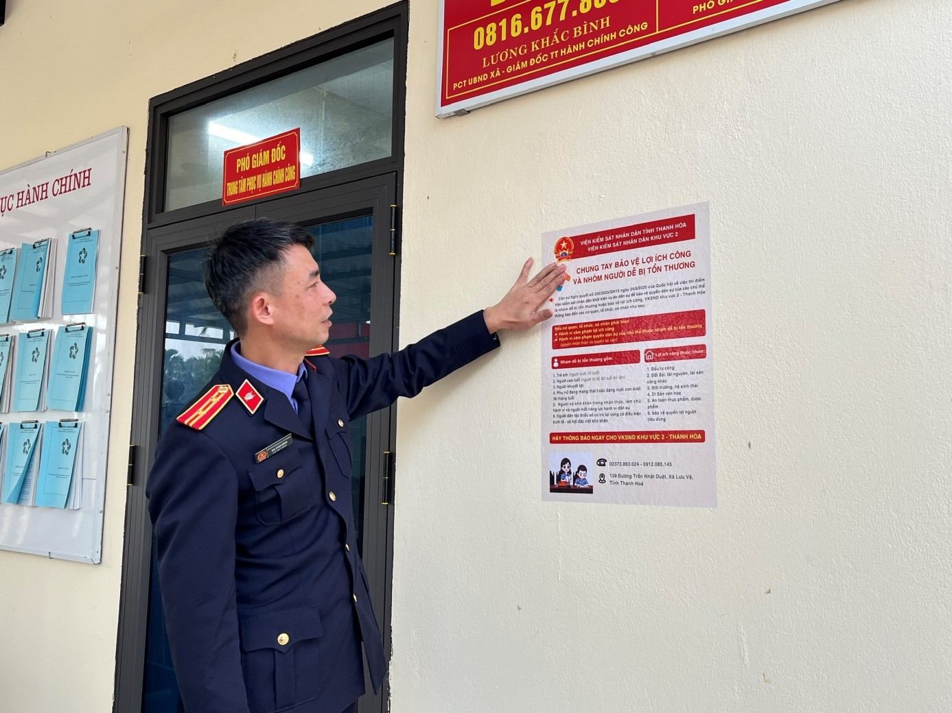 nh: Đồng chí Mai Xuân Đồng, Phó Viện trưởng VKSND khu vực 2 treo áp phích tuyên truyền tại UBND xã